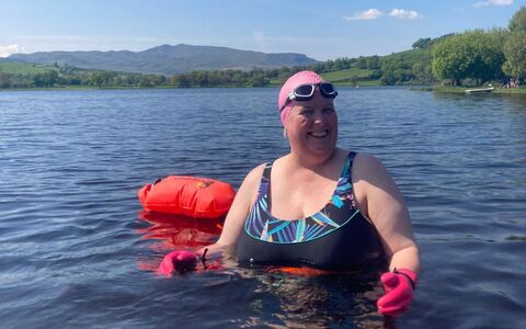 A photo of a lady swimming in Llyn Tegid with Arenig mountain in the background