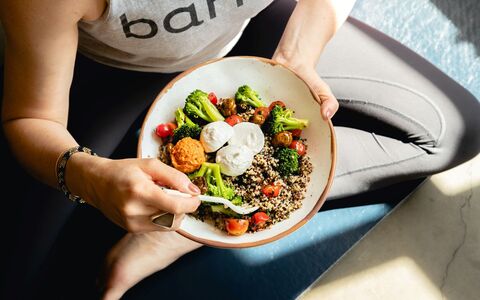 A person sitting in yoga position with a bowl of vegan food