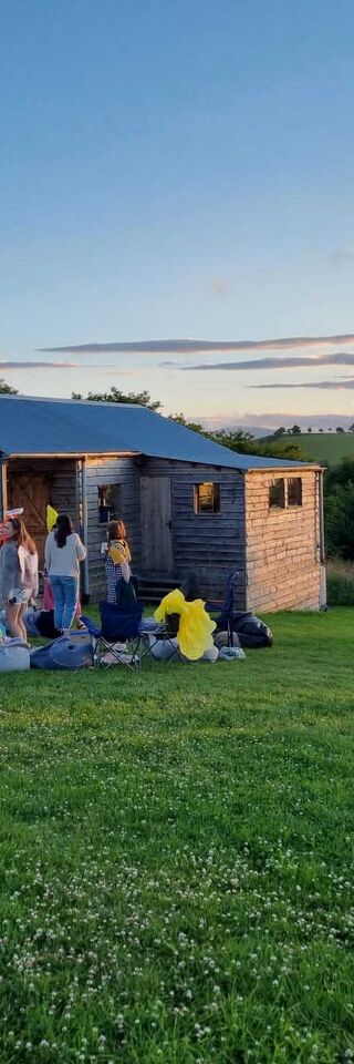 A group of women in fancy dress in front of a log cabin at sunset