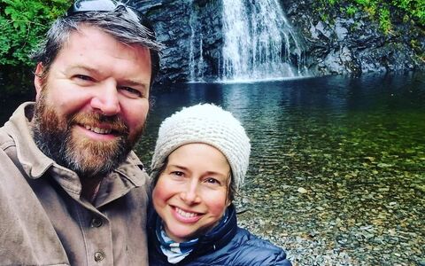 A photo of a couple standing in front of a waterfall