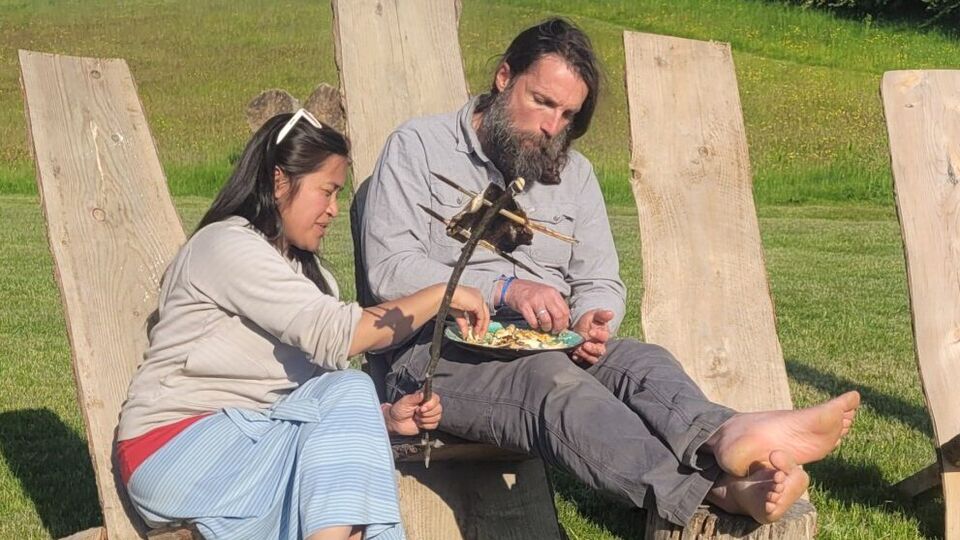 A man and a woman sitting on wooden star gazer chairs eating mindfully