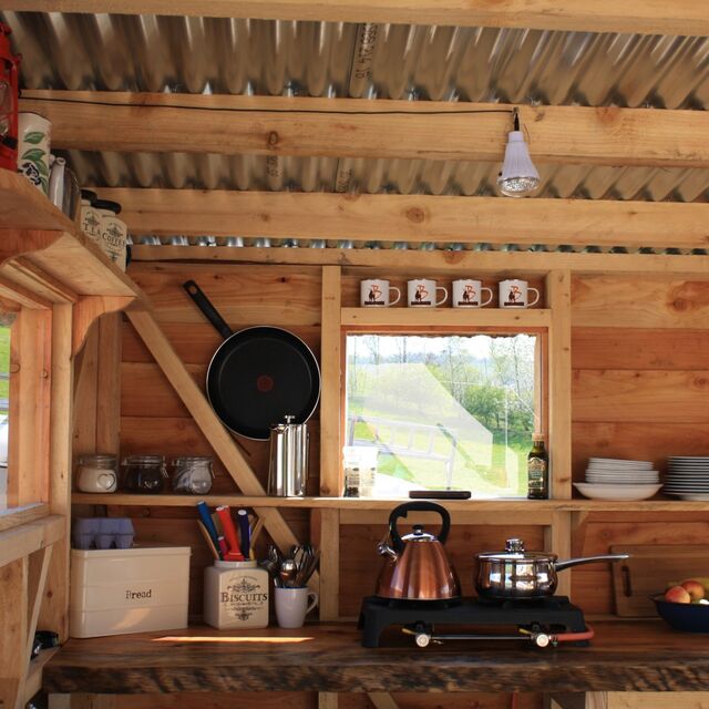 A photo of a camp kitchen showing a kettle and a saucepan on a gas hob